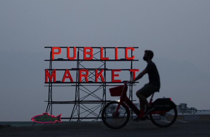 SEATTLE, WA - SEPTEMBER 11: Wildfire smoke obscures the view of Elliott Bay as a person bikes past a Pike Place Market sign on September 11, 2020 in Seattle, Washington. According to reports, air quality is expected to worsen as smoke from dozens of wildfires in forests of the Pacific Northwest and along the West Coast descends onto the region.   Lindsey Wasson/Getty Images/AFP
== FOR NEWSPAPERS, INTERNET, TELCOS & TELEVISION USE ONLY ==
