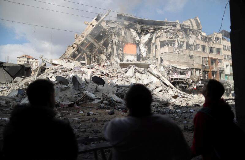 Palestinians look at the remains of a flattened tower building. Reuters