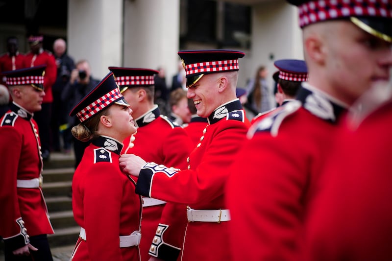 A member of the Scots Guards helps a colleague with her uniform before the Black Sunday Parade, at the chapel of the Guards Museum in Westminster. PA