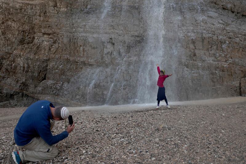 People take picture near a flash-flood at Qumran Canyon waterfalls, near the Dead Sea, following heavy rain in the region. AFP