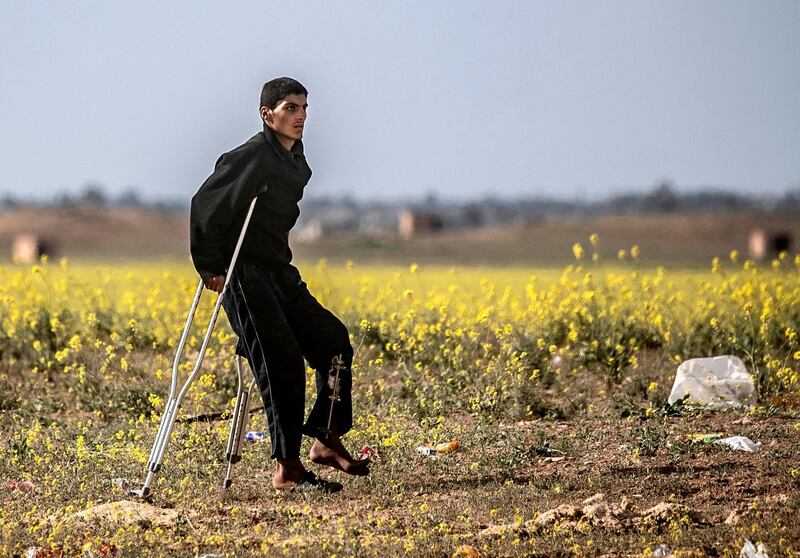 A man walks using a crutch towards a screening point. AFP