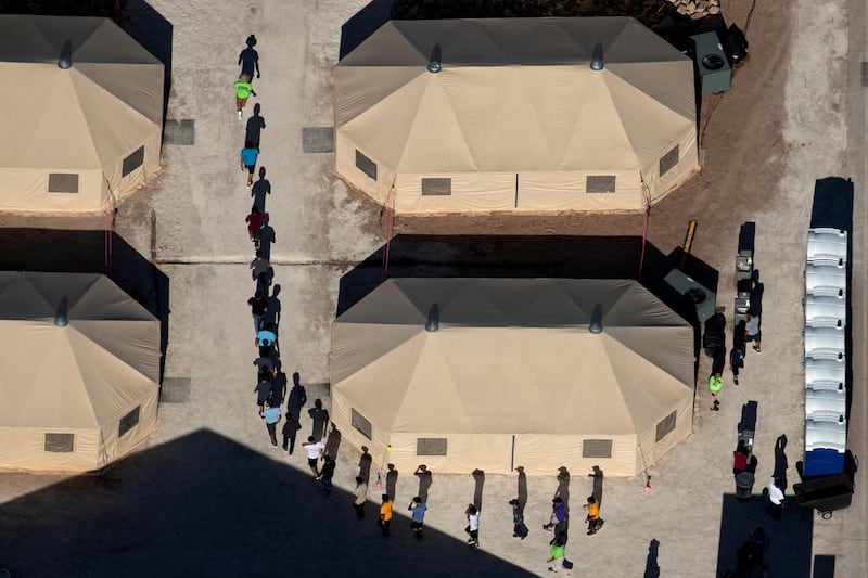Immigrant children are led by staff in single file between tents at a detention facility next to the Mexican border in Tornillo, Texas, on June 18, 2018. Reuters