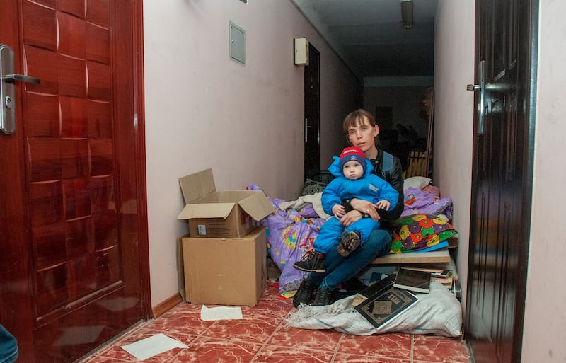 A woman and a child are forced to sit on the corridor of a building in Kharkiv that is used as a bomb shelter. EPA