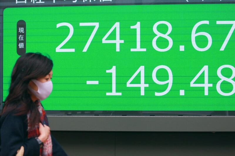 A woman walks by an electronic stock board of a securities firm in Tokyo, Wednesday, Dec. 30, 2020. Asian shares were mixed Wednesday after a lackluster day on Wall Street, as the boost from President Donald Trumpâ€™s signing of the coronavirus relief package faded.(AP Photo/Koji Sasahara)