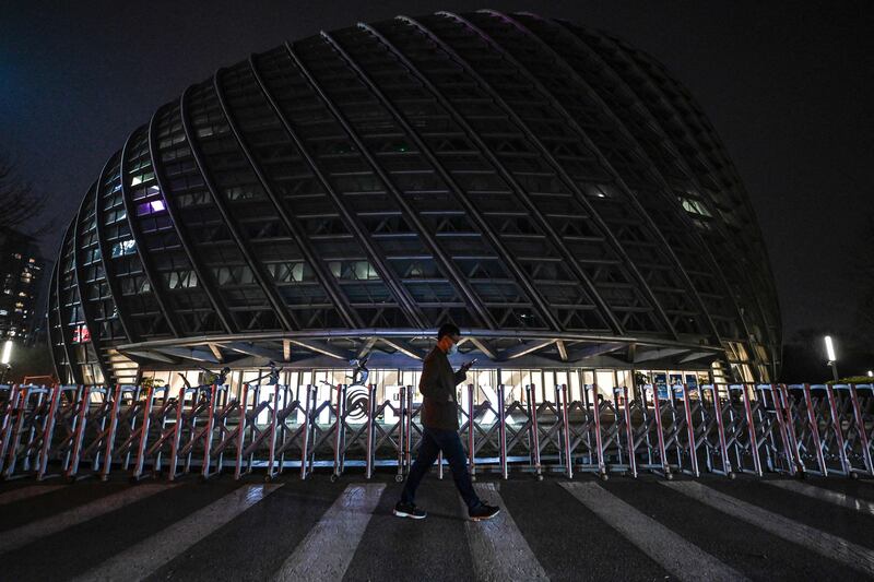 A man walks past the Phoenix Center after its lights are turned off for the Earth Hour environmental campaign in Beijing. AFP
