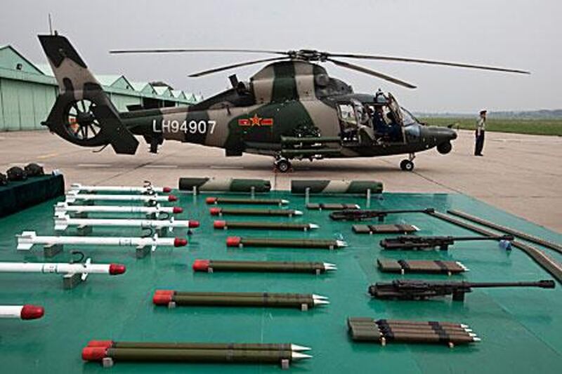 A military officer stands near a Z-9WZ attack helicopter and weapons, designed and manufactured by China during its open day to world media.