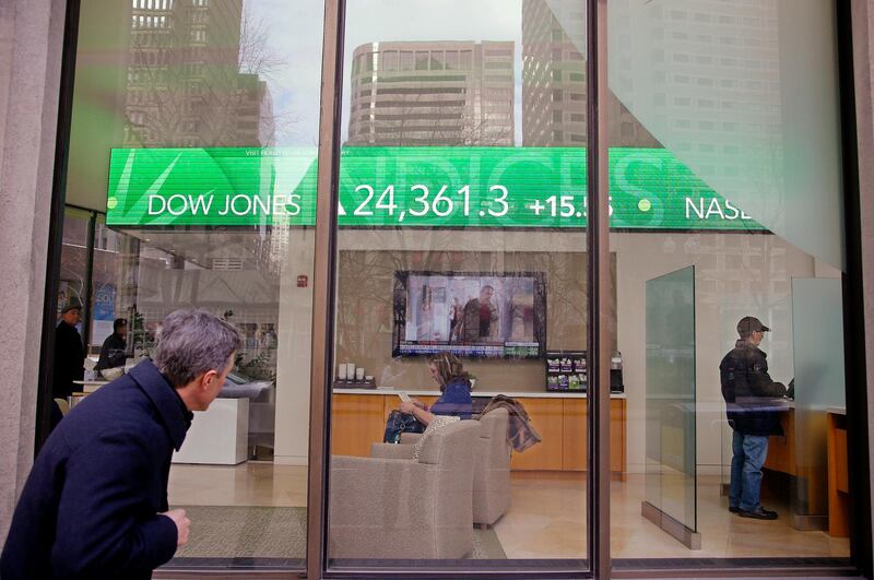 FILE- In this Feb. 6, 2018, file photo, a passer-by peers in the window while investors congregate inside at the Fidelity Investments office on Congress Street as the ticker displays stock market numbers in Boston. A plunge in stock prices always stings, but this recent one dug deeper because more of the country has become exposed to the ups and downs of the market, particularly older Americans. (AP Photo/Stephan Savoia, File)