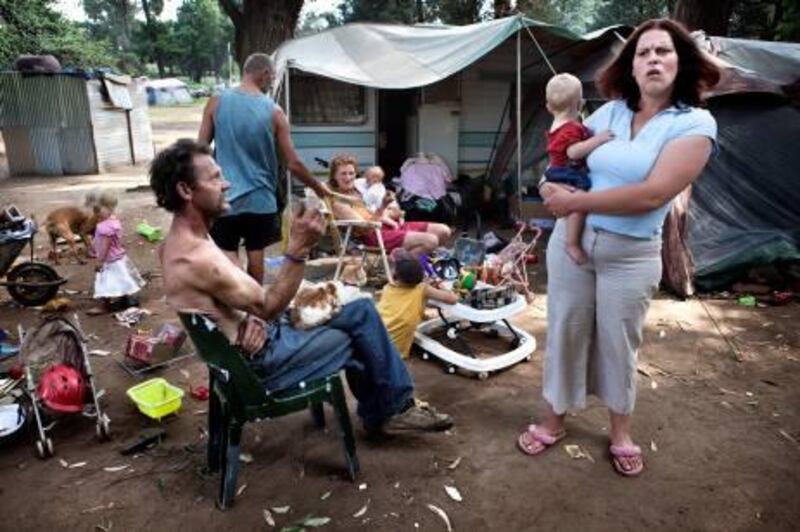 Andre Coetzee, 57, (L) sits with a neighbouring family at a squatter camp for poor white South Africans at Coronation Park in Krugersdorp, March 13, 2010.   A shift in racial hiring practices and the recent global economic crisis means many white South Africans have fallen on hard times. Researchers now estimate some 450,000 whites, of a total white population of 4.5 million, live below the poverty line and 100,000 are struggling just to survive in places such as Coronation Park, a former caravan camp currently home to more than 400 white squatters.   BEST QUALITY FILE                           REUTERS/Finbarr O'Reilly (SOUTH AFRICA - Tags: SOCIETY BUSINESS) FRANCE MAGAZINES OUT. FOR MORE INFORMATION, PLEASE CONTACT YOUR LOCAL SALES REPRESENTATIVE