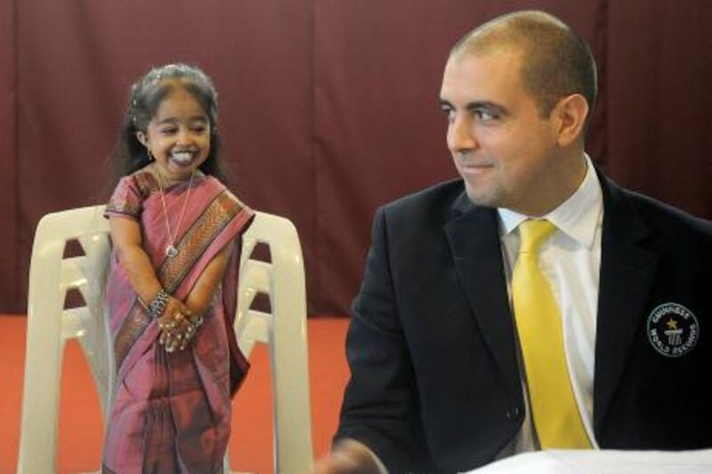 Guinness World Records adjudicator Rob Molloy and Jyoti Amge (L), 18, attend a news conference in Nagpur on December 16, 2011. Amge was officially announced by the Guinness World Records on December 16 the world's "shortest woman living (mobile)" measured as 62.8cm (24.7 inches) and will take the title from US woman Bridgette Jordan, previously held the record at 69.5 cm (27.4 in). AFP PHOTO/Punit PARANJPE
 *** Local Caption ***  484636-01-08.jpg