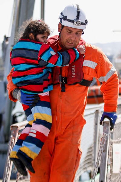 A rescuer carries a child as they disembark from the 'Abeille Languedoc'. AFP
