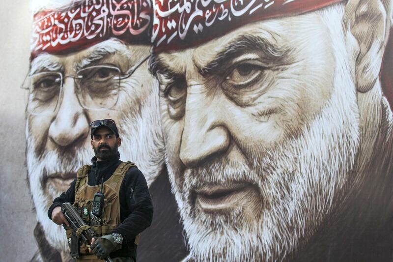 An Iraqi fighter of the Hashed al-Shaabi stands guard beneath posters displaying portraits of slain Iranian Revolutionary Guards commander Qasem Soleimani (R) and Abu Mahdi al-Muhandis - the deputy chief of Iraq's largely pro-Iran Hashed al-Shaabi paramilitary force - ahead of the first anniversary of their killing in a US drone strike, in the Iraqi capital Baghdad. The US sent shock waves through the Middle East, with the targeted killing of Iran's General Qasem Soleimani and his Iraqi lieutenant, which infuriated the Islamic republic and its allies. AFP