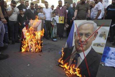 TOPSHOT - Palestinian demonstrators burn pictures of US President Donald Trump and Israeli Prime Minister Benjamin Netanyahu during a demonstration against the plans to annex parts of the occupied West Bank on May 30, 2020, in Nablus in the occupied West Bank.  / AFP / JAAFAR ASHTIYEH

