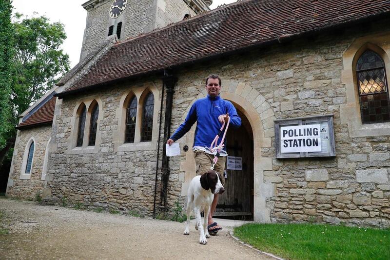 A man with a dog leaves a church set up as a polling station in Stadhampton, near Oxford. AFP 