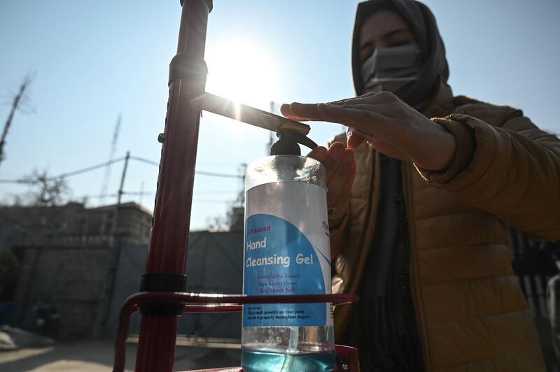 A student sanitises her hands before entering a college which reopened following nearly 11 months of closure in Srinagar. AFP