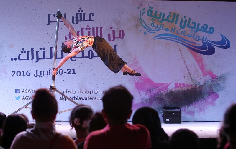 Visitors watch a performer on the open air stage at the Al Gharbia Watersports Festival.