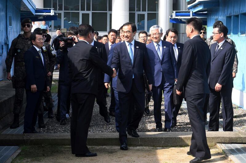 South Korean Unification Minister Cho Myoung-gyon, center, shakes hands with a North Korean official as he crosses to North Korea for the meeting at the northern side of Panmunjom in the Demilitarized Zone, North Korea, Monday, Aug. 13, 2018. Senior officials from the rival Koreas met Monday to set a date and venue for a third summit between South Korean President Moon Jae-in and North Korean leader Kim Jong Un, part of an effort to breathe new life into resolving the nuclear standoff between Washington and Pyongyang. (Korea Pool/Yonhap via AP)