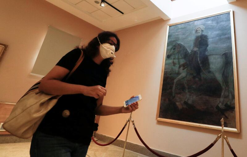 An Egyptian woman wears a protective face mask as she walks in front of a painting at The Royal Carriages Museum after its reopening in Cairo, Egypt. Reuters