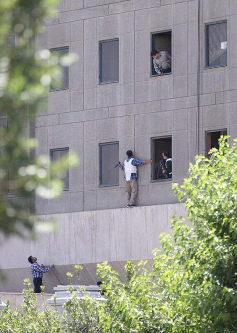 A policeman clings on to the parliament building as he checks for the assailants in the next room. Omid Vahabzadeh / Tima via Reuters