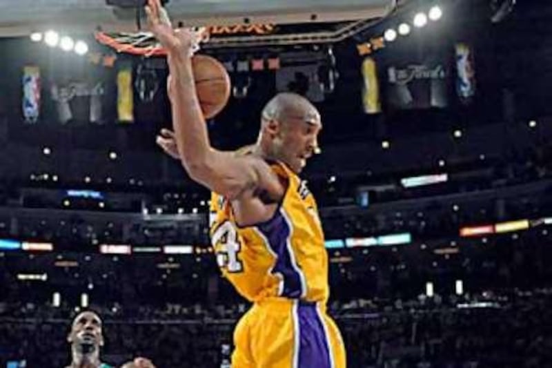 The Lakers guard Kobe Bryant dunks the ball in the second half as Celtics forward Kevin Garnett looks on.