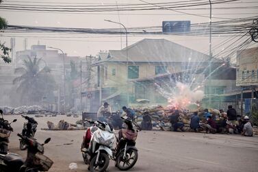 Firecrackers explode as protesters take cover behind a barricade during a demonstration against the military coup in Mandalay, Myanmar, on March 21, 2021. Reuters