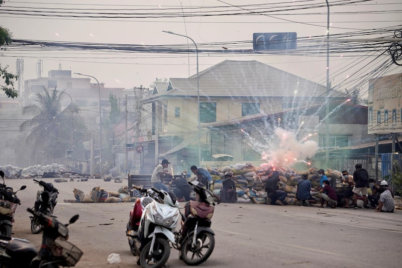 Firecrackers explode as protestors take cover behind a barricade during a demonstration against the military coup in Mandalay, Myanmar March 21, 2021. REUTERS/Stringer
