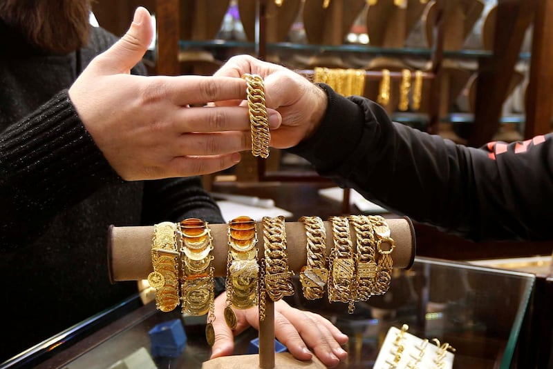 A salesman handles gold bracelet to a customer inside a jewellery shop in Beirut, Lebanon. REUTERS