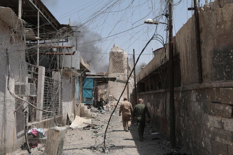 Soldiers walk down a narrow alleyway towards the base of Al Nuri Mosque's famous Al Hadba minaret, destroyed by ISIL on June 21.  Florian Neuhof  / The National