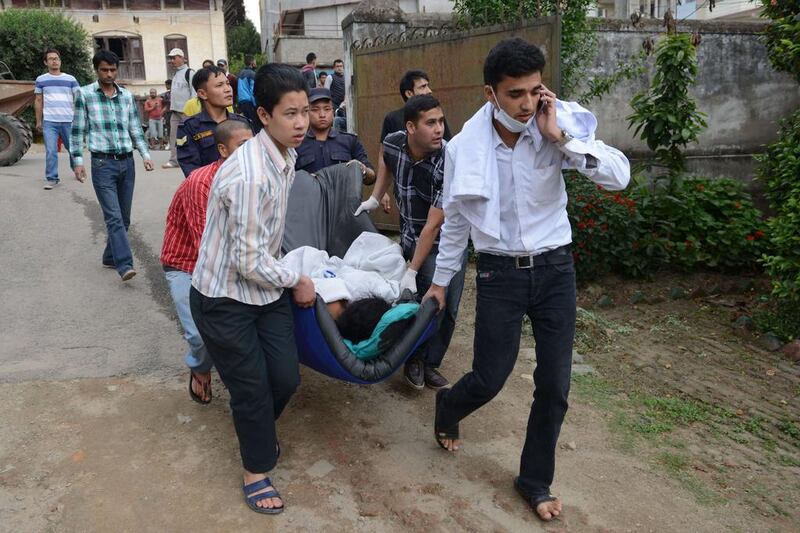Nepalese health workers carry injured people into an open area following an 7.9 earthquake, at Lalitpur on the outskirts of Kathmandu on April 25, 2015.  A powerful 7.9 magnitude earthquake struck Nepal, causing massive damage in the capital Kathmandu with strong tremors felt across neighbouring countries.  AFP PHOTO / PRAKASH MATHEMA