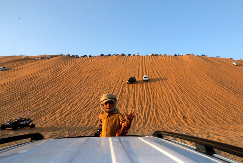 Abu Dhabi, United Arab Emirates, January 2, 2020.  4X4 goers watch different desert 4X4 mobiles go up the Al Al Moreeb Dune at the 2020 Liwa Festival.
Victor Besa / The National
Section:  NA
Reporter:  Haneen Dajani
