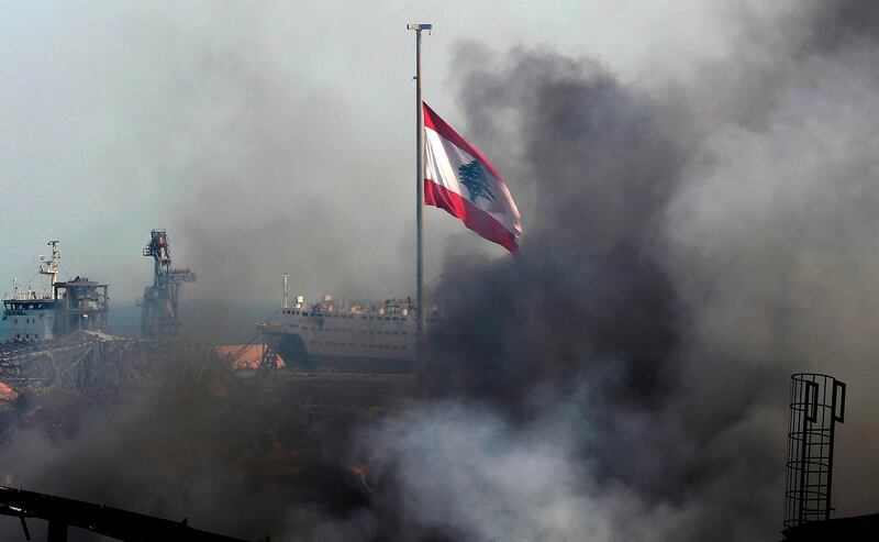 A Lebanese flag flutters amid billowing smoke. AFP