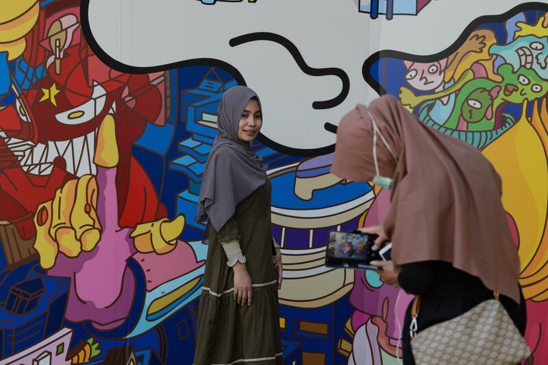 Two Indonesian foreign domestic workers pose for photos in front of the Bo Law animation artwork at the Hong Kong Museum of Art in Hong Kong. AFP