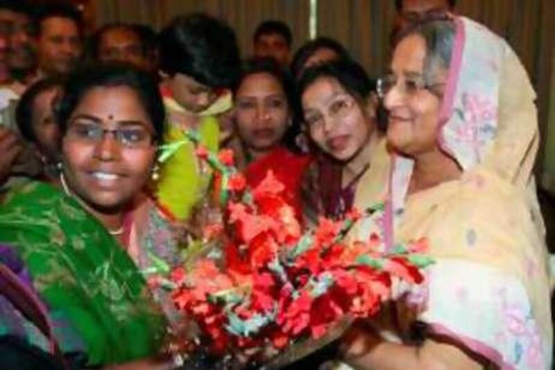 Bangladesh’s former Prime Minister and Awami League President Sheikh Hasina, right, receives flowers from supporters at her residence in Dhaka, Bangladesh, Tuesday, Dec. 30, 2008. Bangladeshi voters handed the alliance led by Hasina a landslide victory in results announced Tuesday, as the troubled South Asian nation returned to democracy after two years of military-backed rule. (AP Photo/Pavel Rahman) *** Local Caption ***  DHA101_Bangladesh_Election.jpg