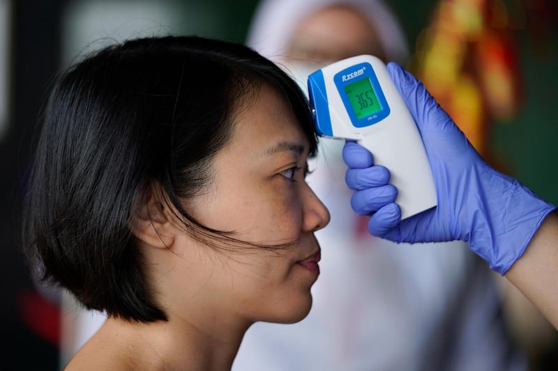 A nurse checks the temperature of a visitor as part of the coronavirus screening procedure at a hospital in Kuala Lumpur. AP Photo