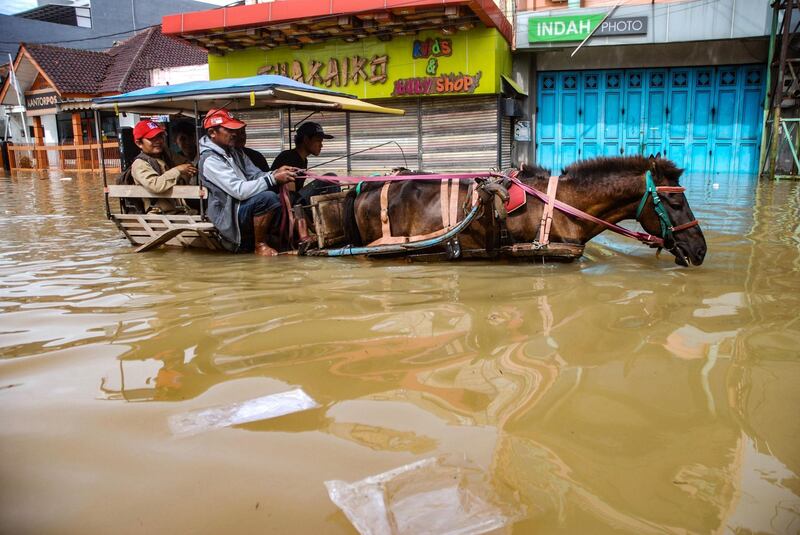 Residents commuting along a flooded road in Dayeuhkolot village in Bandung, West Java province.  AFP
