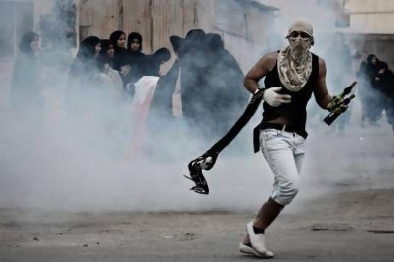 A Bahraini Shiite protester, holding petrol bombs, runs for cover from tear gas fired by riot police during clashes in the village of Samahij on November 13.