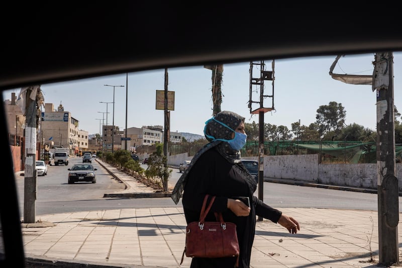 A woman wears a protective face mask as she walks in the Baqa'a Palestinian refugee urban camp, near Amman, Jordan.  EPA
