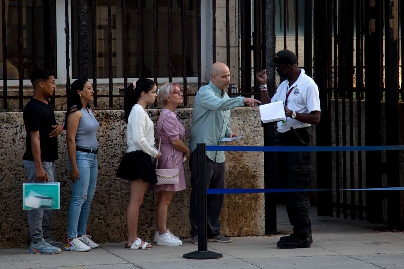 People stand in line outside the embassy on the day of its reopening for visa and consular services. AP