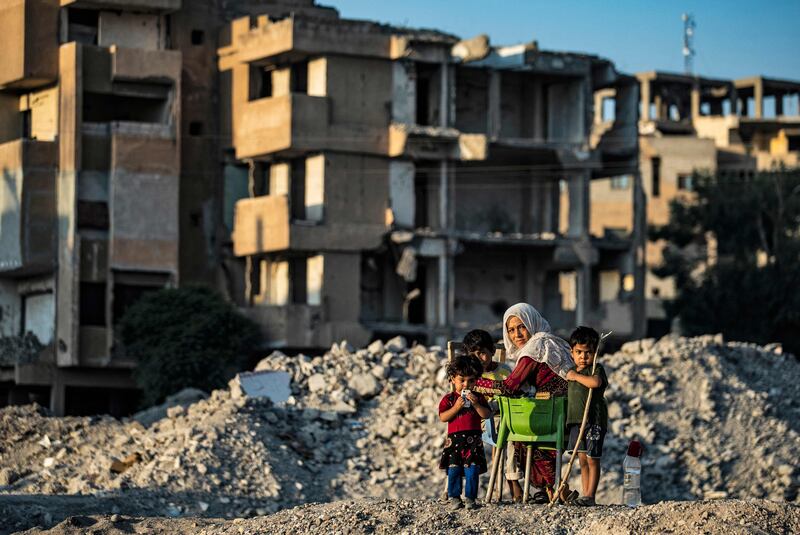 A Syrian woman and children gather amidst rubble in the city of Raqqa, the former Syrian capital of ISIS. All photos: AFP