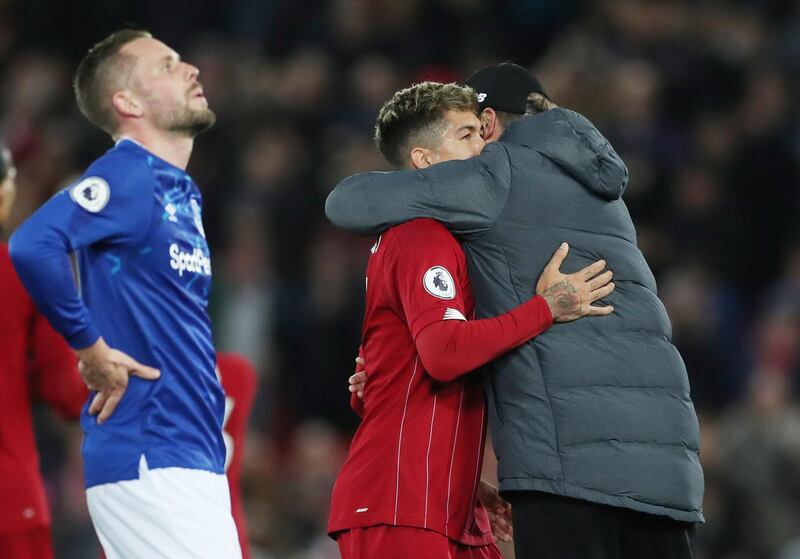 Liverpool manager Juergen Klopp celebrates with Roberto Firmino as Everton's Gylfi Sigurdsson looks dejected. Reuters