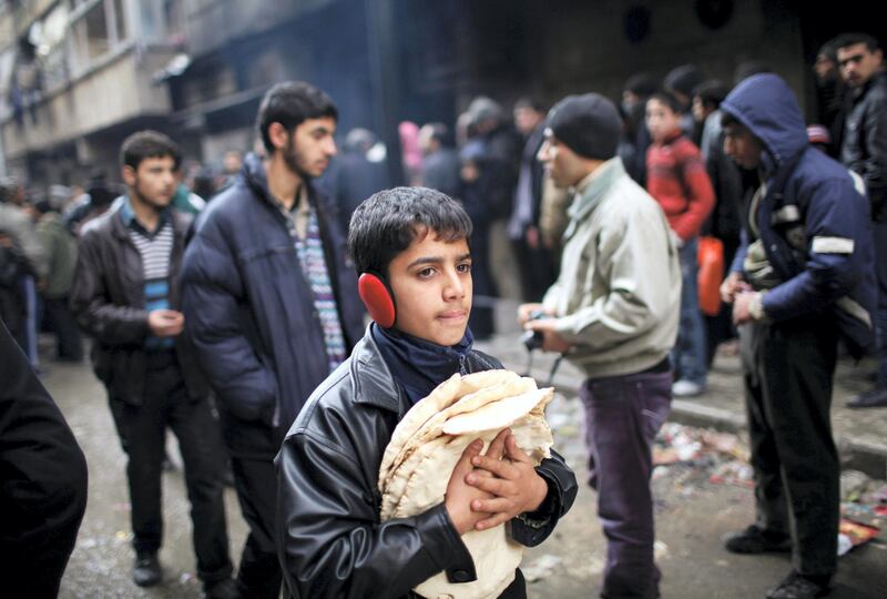 A boy holds pita bread as others stand in line outside a bakery in Aleppo December 21, 2012.  REUTERS/Ahmed Jadallah (SYRIA - Tags: SOCIETY)
