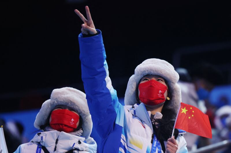 A woman wearing a face mask holds a Chinese national flag before the Beijing 2022 Winter Olympics. Reuters