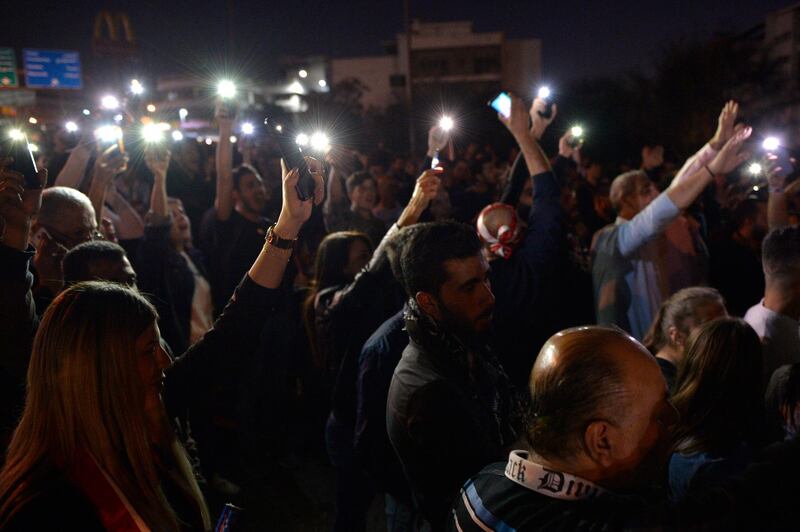Protesters lighting up their phones and shout slogans as they block the highway leading to the Presidential palace during a protest to demand the formation of a new government in Baabda.  EPA