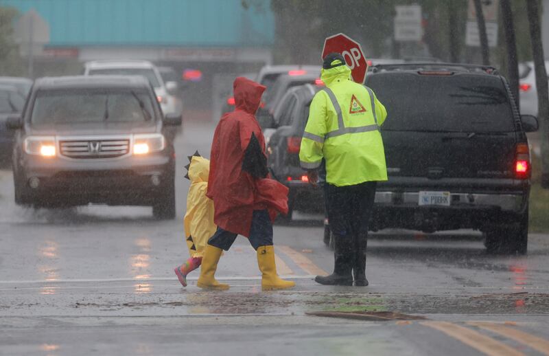 A school crossing guard helps people cross the street in Dania, Florida. AP