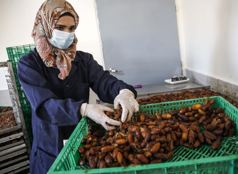 A mask-clad Palestinian woman sorts out freshly harvested dates at a packaging factory in Khan Yunis, in the southern Gaza Strip. The dates are harvested in October following the first rain.  AFP