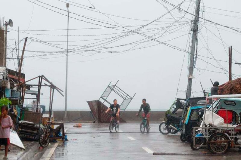 Residents walk past a toppled structure as waves batter the coast of Sorsogon province. AP Photo