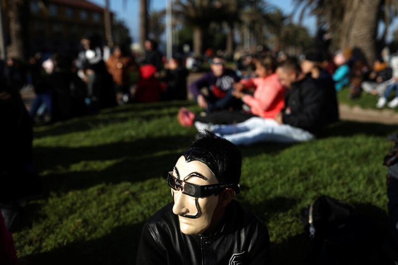 A man wears a mask and a pair of eclipse glasses to observe a solar eclipse at La Serena, Chile. Reuters