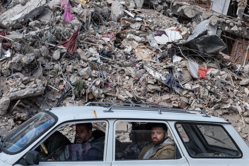 People drive past a collapsed buildings in Hatay, in Turkey. Getty