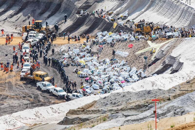 Climate activists use blankets to protect against the sun as they are encircled by police and cars after entering the grounds of the Garzweiler brown coal mine in Garzweiler, western Germany, during a weekend of massive protests in a growing "climate civil disobedience" movement.  AFP