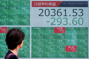 A woman walks past an electronic stock board showing Japan's Nikkei 225 index at a securities firm in Tokyo Thursday. Asian stock markets followed Wall Street lower on Thursday after the Dow Jones Industrial Average plunged on mounting fears of a possible recession. AP