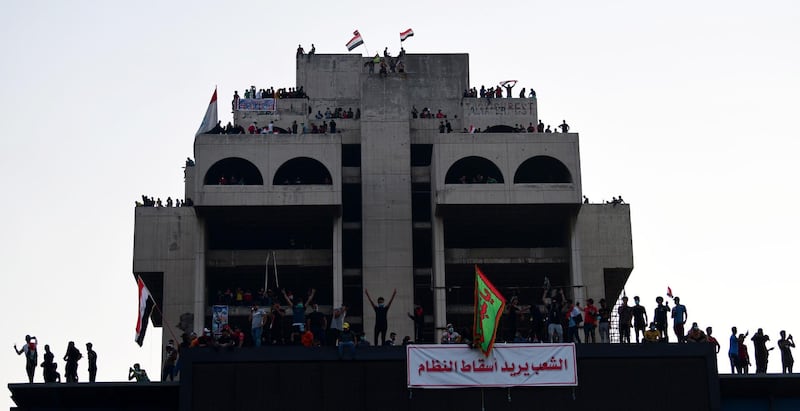 Iraqi protesters chant slogans as they stand over a high building with a banner reading in Arabic 'people want to bring down the regime' during a demonstration at al-Tahrir square, in central Baghdad, Iraq. EPA